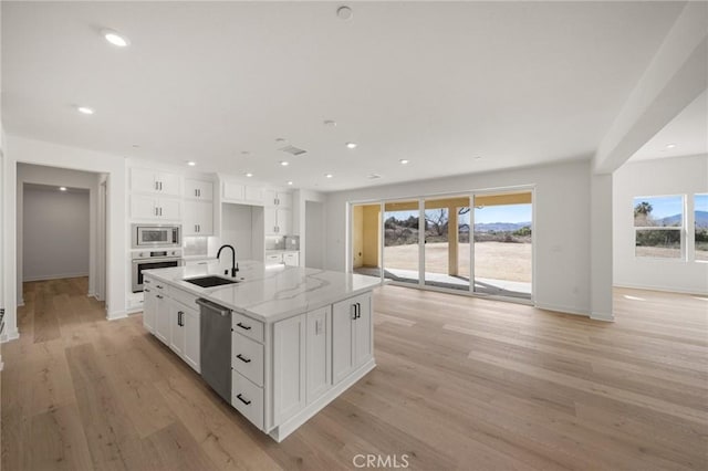 kitchen with white cabinets, light wood-type flooring, stainless steel appliances, and a sink