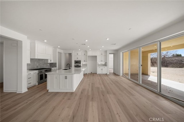 kitchen featuring white cabinets, decorative backsplash, stainless steel appliances, and a sink