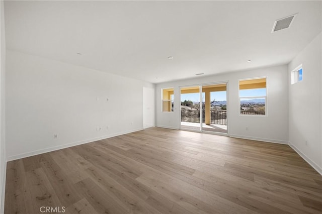 spare room featuring baseboards, visible vents, and wood finished floors