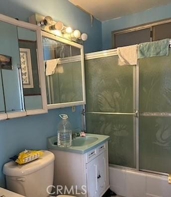 full bathroom featuring vanity, toilet, and shower / bath combination with glass door