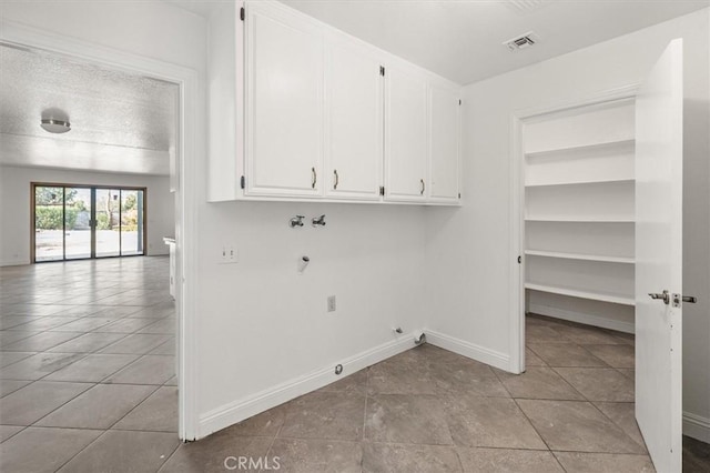 washroom with gas dryer hookup, light tile patterned floors, cabinets, washer hookup, and a textured ceiling