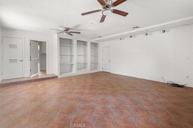 empty room featuring built in shelves and ceiling fan