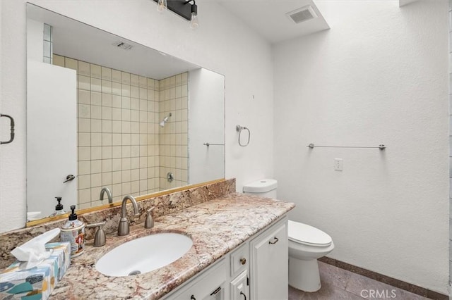 bathroom with vanity, a tile shower, and toilet