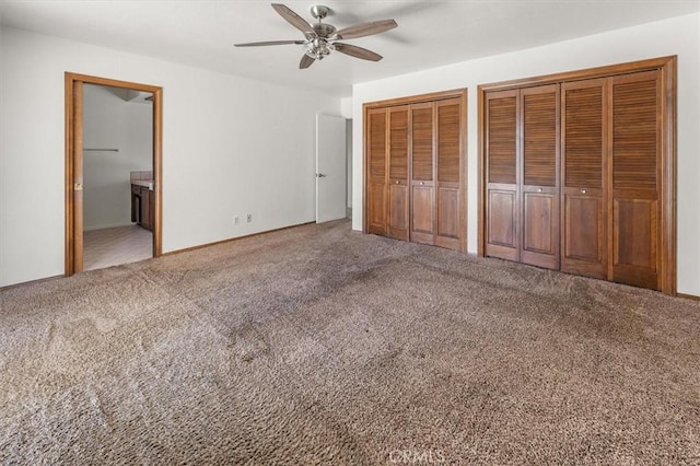 unfurnished bedroom featuring connected bathroom, multiple closets, ceiling fan, and carpet flooring