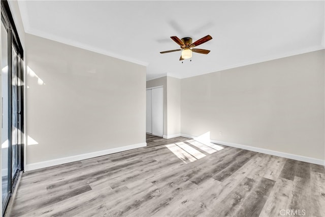 empty room featuring ceiling fan, light wood-type flooring, and crown molding