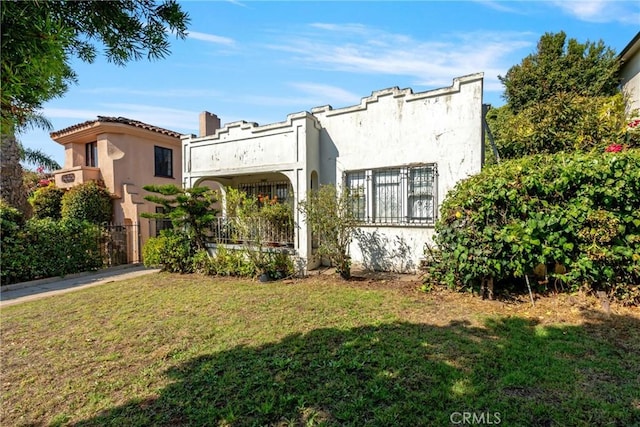 rear view of house featuring a yard and a balcony