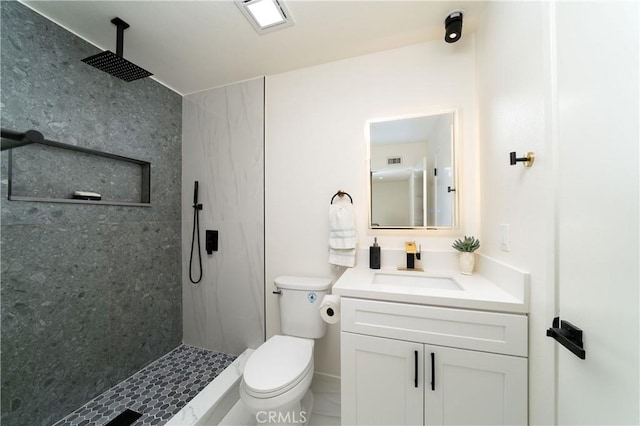 bathroom with tiled shower, vanity, toilet, and tile patterned flooring