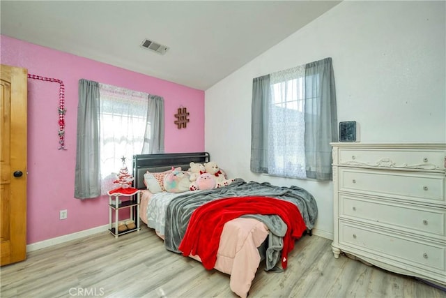 bedroom with lofted ceiling, multiple windows, and light hardwood / wood-style floors