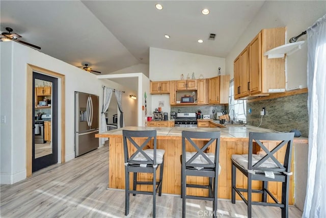 kitchen with stainless steel appliances, lofted ceiling, backsplash, and a kitchen bar