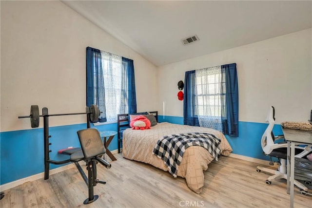 bedroom with lofted ceiling and light wood-type flooring