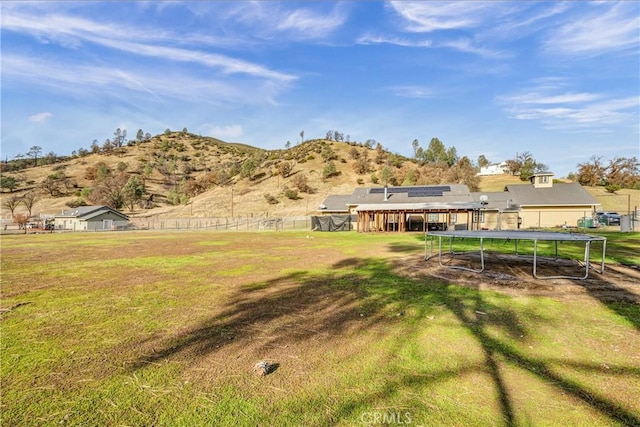 view of yard featuring a mountain view, a trampoline, and a rural view