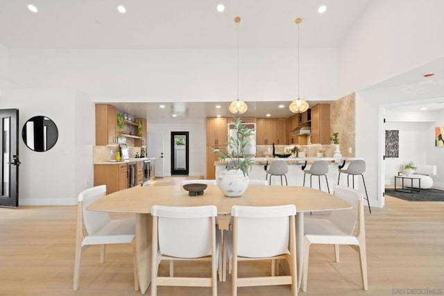 dining space with wine cooler and light hardwood / wood-style floors