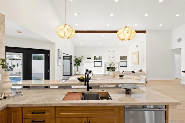 kitchen with high vaulted ceiling, sink, light stone countertops, light wood-type flooring, and decorative light fixtures