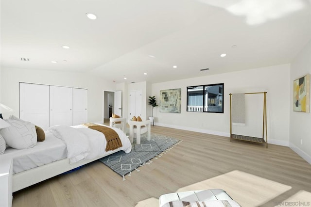 bedroom featuring light hardwood / wood-style floors, lofted ceiling, and a closet