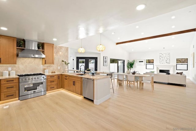 kitchen with lofted ceiling with beams, wall chimney exhaust hood, light wood-type flooring, kitchen peninsula, and stainless steel appliances