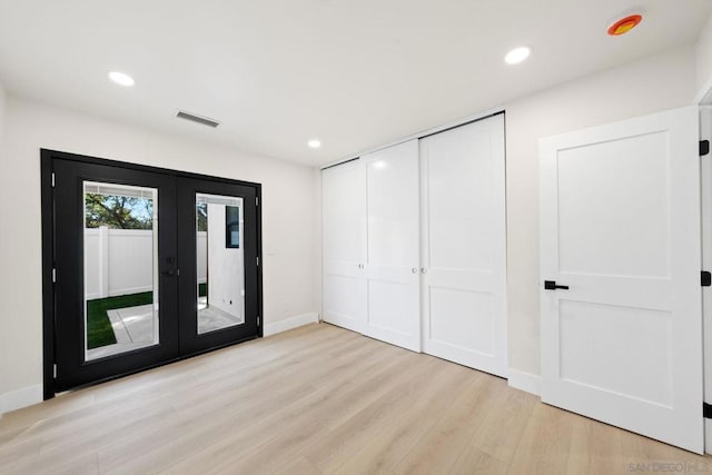 unfurnished bedroom with access to outside, a closet, french doors, and light hardwood / wood-style floors