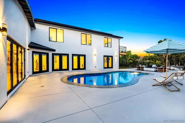 pool at dusk with a patio area