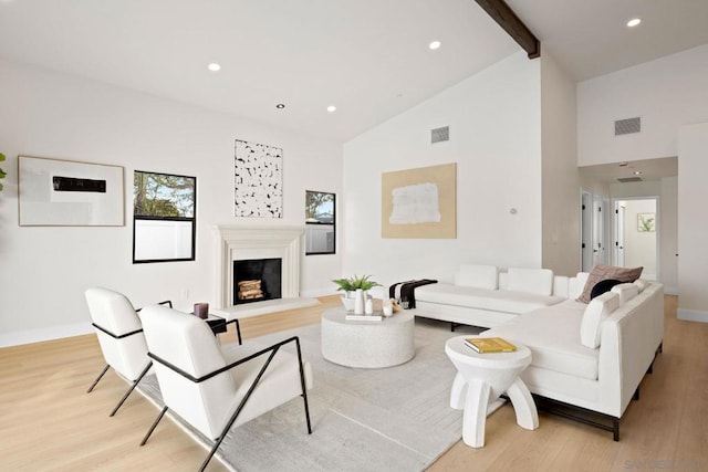 living room with beamed ceiling, high vaulted ceiling, and light hardwood / wood-style flooring