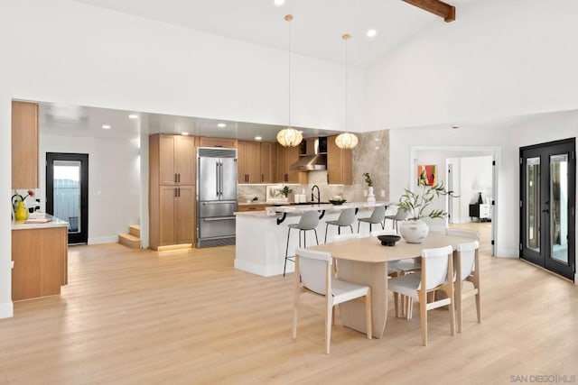 dining room with beam ceiling, light hardwood / wood-style flooring, high vaulted ceiling, and sink