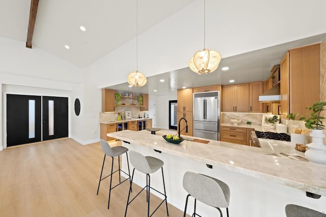 kitchen with stainless steel appliances, hanging light fixtures, range hood, kitchen peninsula, and light wood-type flooring