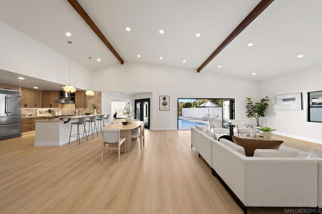 living room featuring beam ceiling, high vaulted ceiling, and light hardwood / wood-style floors