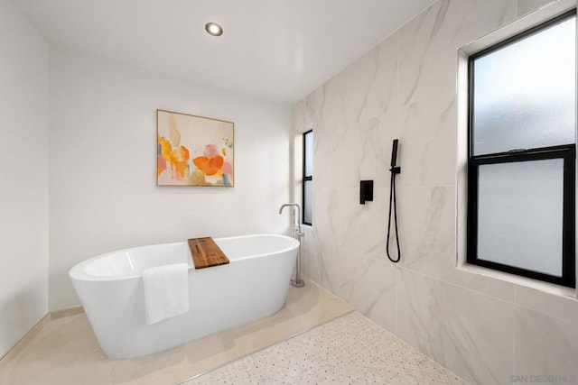 bathroom with a tub to relax in and tile walls