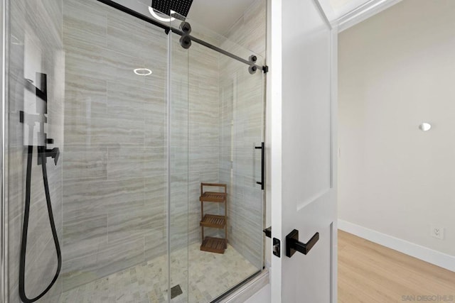 bathroom with hardwood / wood-style flooring and a shower with shower door