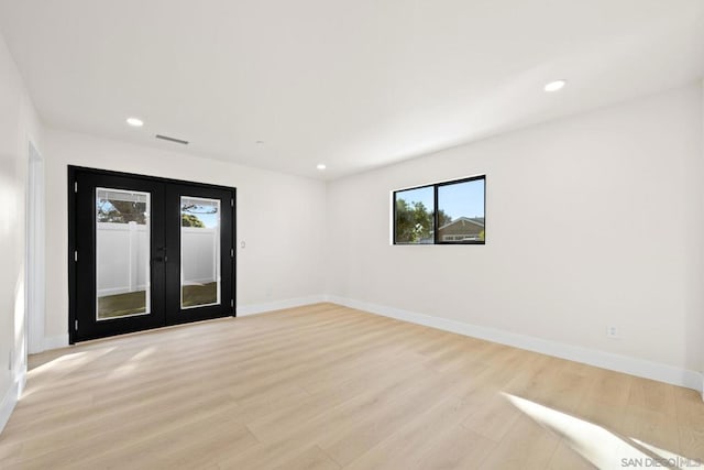 spare room with french doors and light hardwood / wood-style floors