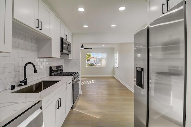 kitchen featuring white cabinets, light stone counters, sink, and appliances with stainless steel finishes