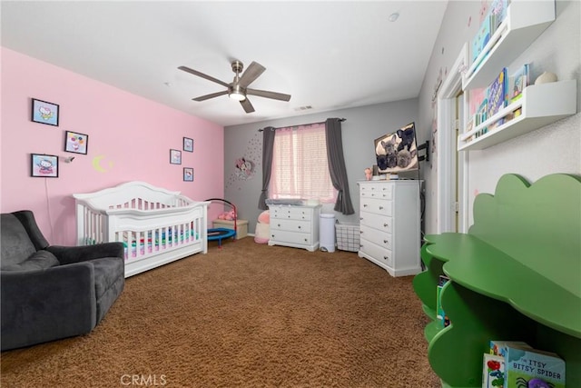 carpeted bedroom featuring ceiling fan and a crib