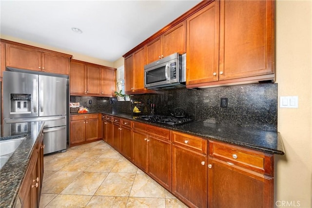 kitchen with light tile patterned floors, stainless steel appliances, tasteful backsplash, and dark stone countertops