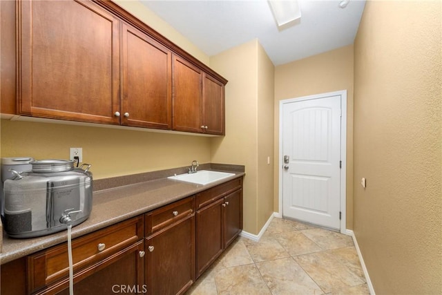 laundry room featuring sink, light tile patterned floors, and cabinets