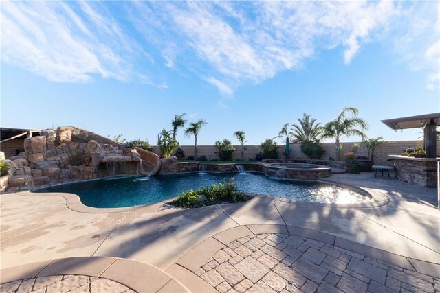 view of swimming pool featuring pool water feature, exterior bar, an in ground hot tub, and a patio