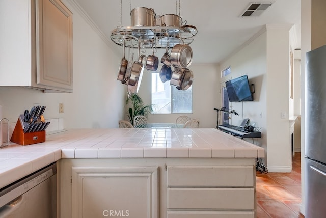 kitchen featuring kitchen peninsula, crown molding, stainless steel appliances, and tile countertops