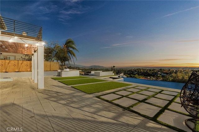 patio terrace at dusk featuring fence