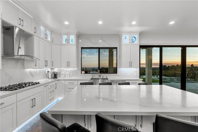 kitchen featuring a breakfast bar, a kitchen island, gas cooktop, and white cabinetry