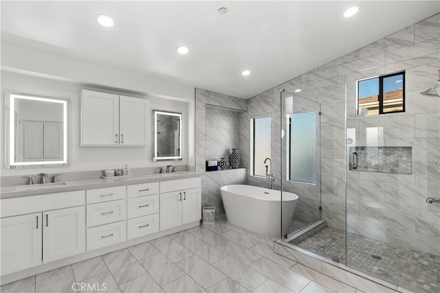 full bathroom with double vanity, a freestanding tub, a sink, and a shower stall