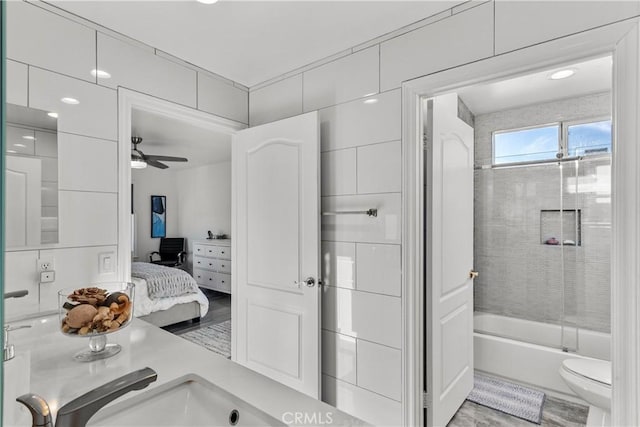 full bathroom with toilet, ceiling fan, bath / shower combo with glass door, and sink