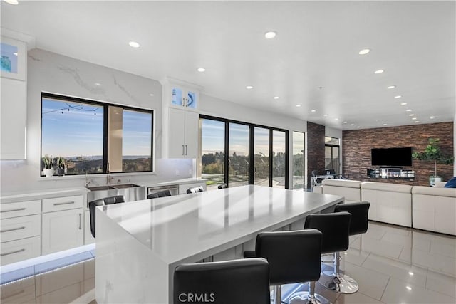 kitchen featuring white cabinetry, a kitchen island, a breakfast bar, and light tile patterned flooring