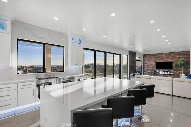 kitchen with light countertops, a breakfast bar area, a center island, and white cabinets