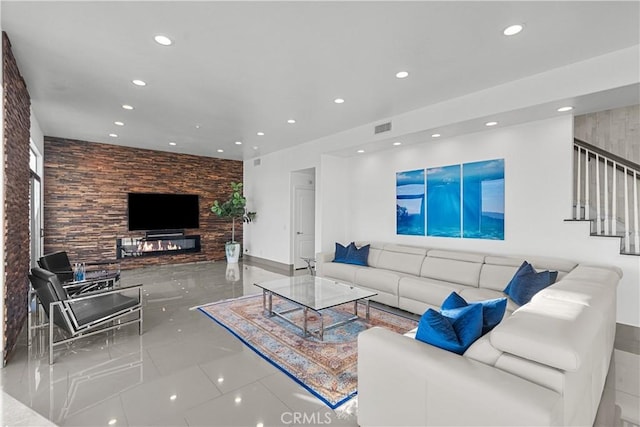 living room with stairway, a glass covered fireplace, visible vents, and recessed lighting