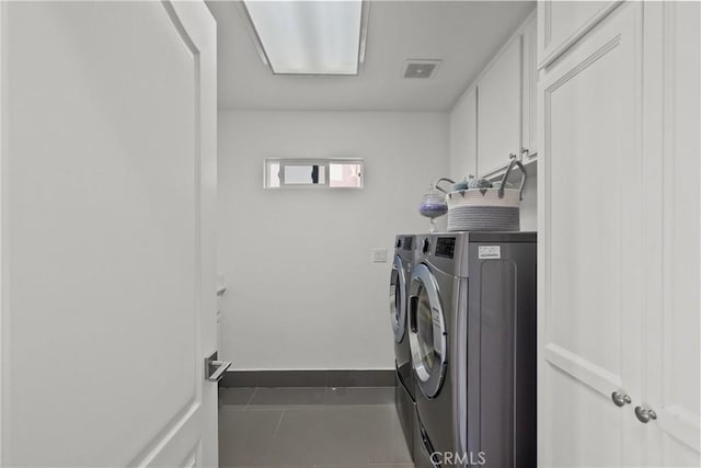 laundry area featuring cabinet space, visible vents, washing machine and dryer, tile patterned flooring, and baseboards