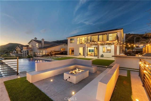 back house at dusk with a fire pit and a patio