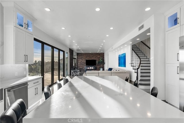 kitchen featuring a breakfast bar, white cabinetry, a center island, dishwasher, and light stone countertops