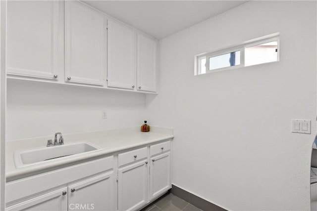 clothes washing area featuring dark tile patterned flooring, a sink, and baseboards