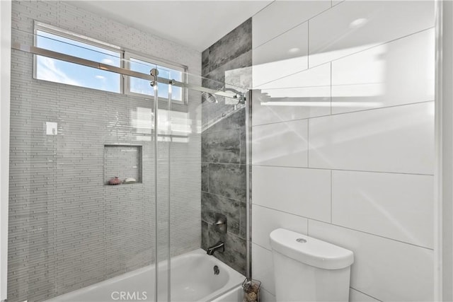 bathroom with enclosed tub / shower combo, tile walls, and toilet