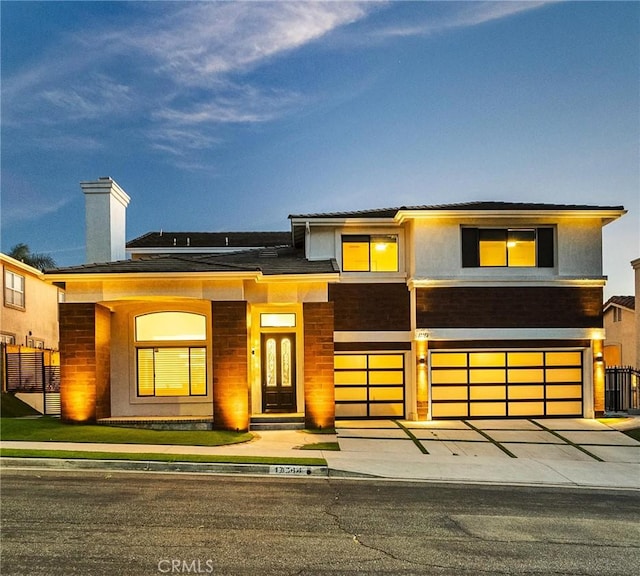 view of front of property featuring a garage, concrete driveway, fence, and stucco siding