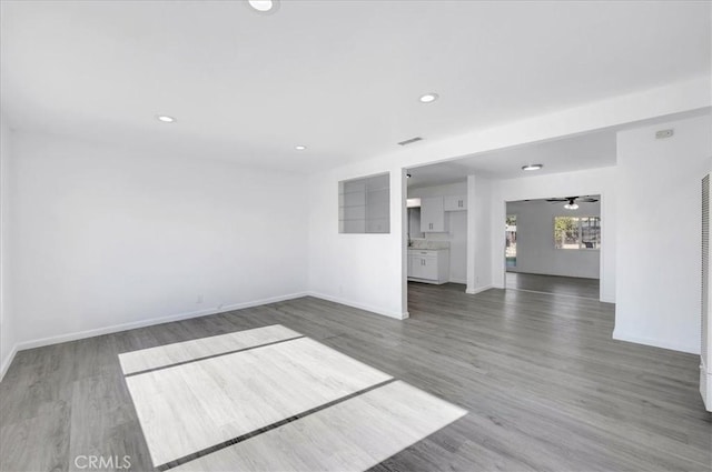 unfurnished living room with ceiling fan and dark wood-type flooring