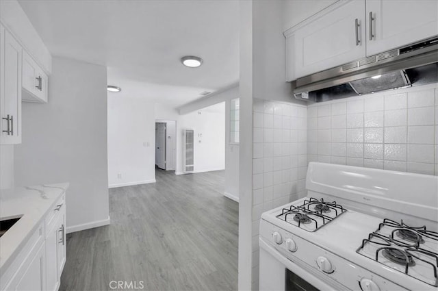 kitchen with white range with gas cooktop, light stone counters, white cabinets, and light hardwood / wood-style floors