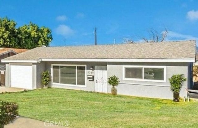 ranch-style home with a garage and a front lawn